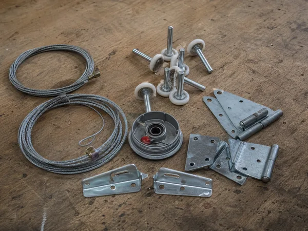 Garage door cables, rollers, hinges and brackets on a workbench