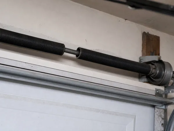 A snapped torsion spring on the shaft above a garage door